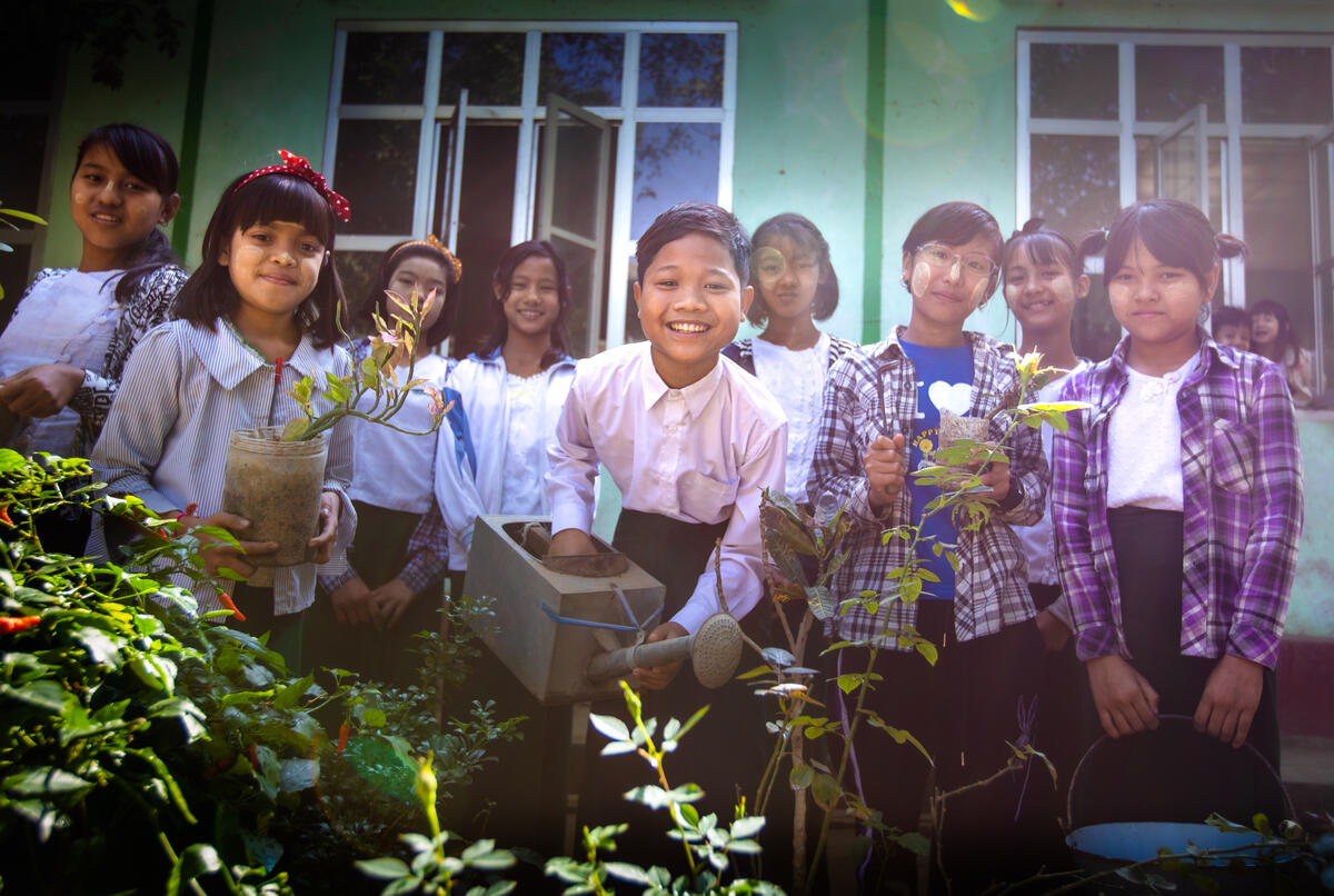 Min planting tree seedlings together with his peers in school.