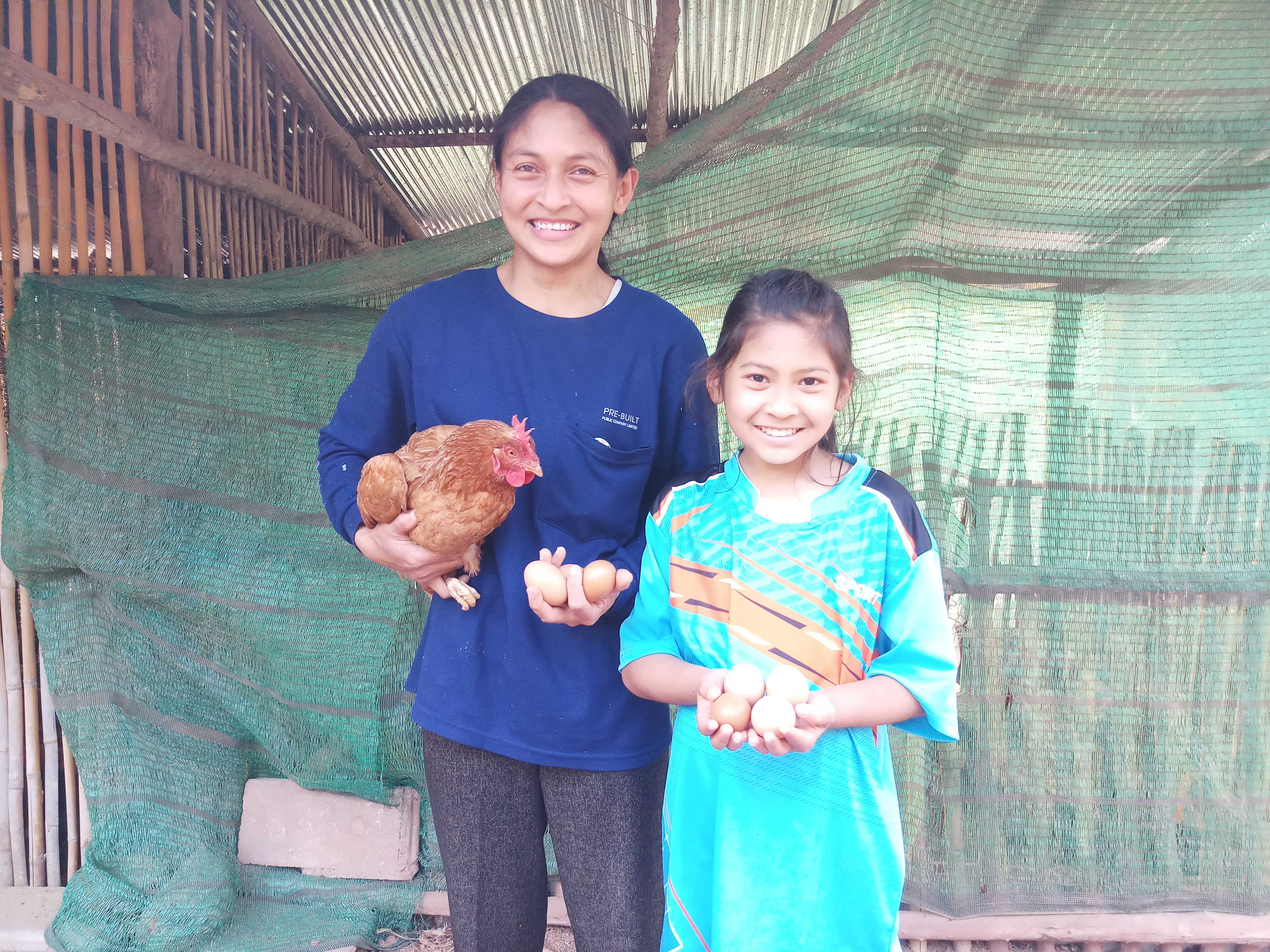 Taengmo and her mum with the agricultural support they've received from World Vision