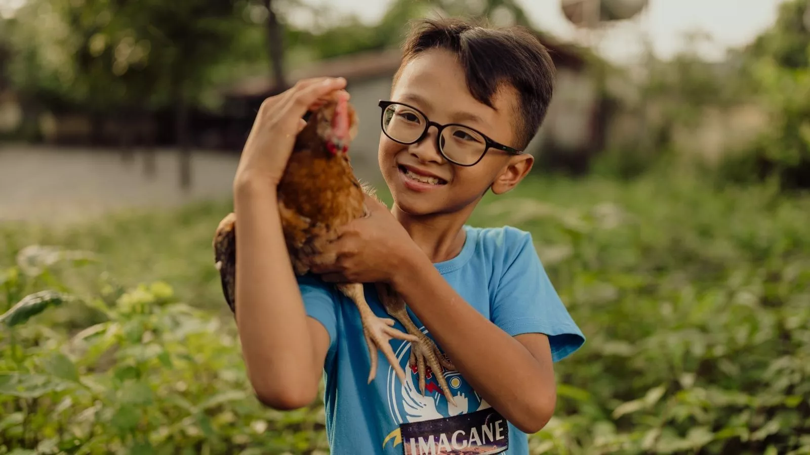 Vietnamese boy holding a chicken and smiling