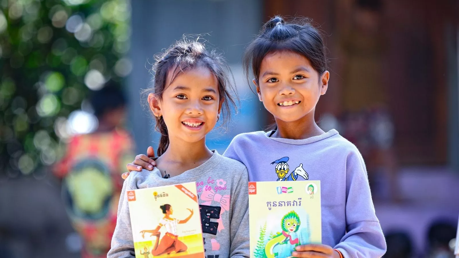 Two Cambodian girls holding books and smiling