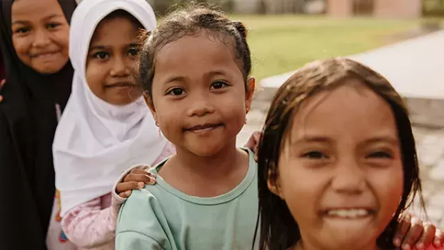 Children standing outdoors in line near buildings