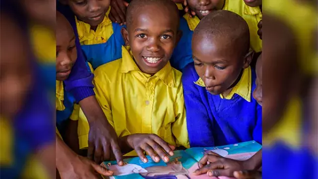 Children in bright uniforms gathered around book