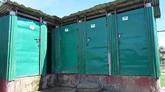 A corner view of a simple structure built from green corrugated metal sheets.