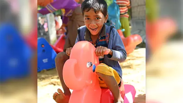 A young boy smiling while playing on a toy ride.