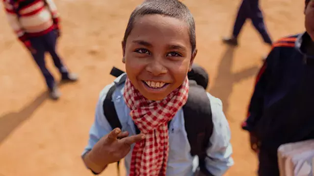Youth in blue shirt with scarf standing in schoolyard