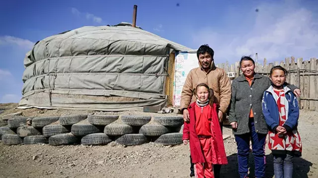 Group standing outside yurt with tires at base