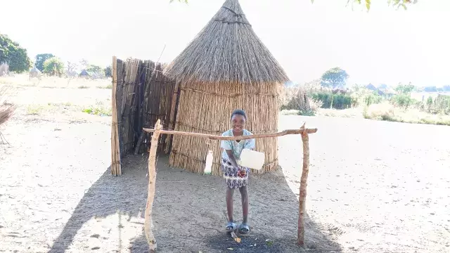 boy in sioma zambia washing his hands with clean water and soap outside of his home