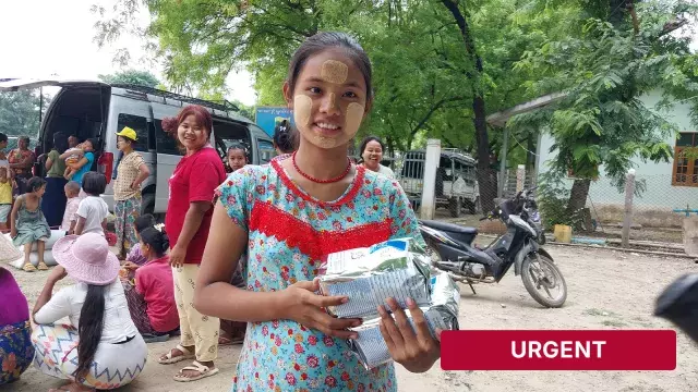 Person holding aid packages with urgent banner nearby